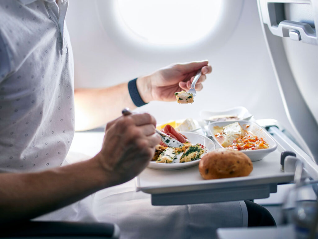 Passager mangeant un repas sur la tablette d'un siège